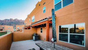 A building with a flat roof, a covered patio area, and a view of mountains in the background. - Sandstone Sanctuary | Moab Townhome w/ Pool & Hot Tub (Moab)