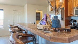 A kitchen with a wooden countertop, a vase with wheat stalks, and a basket of magazines. - Sandstone Sanctuary | Moab Townhome w/ Pool & Hot Tub (Moab)