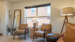 A room with two leather chairs, a floor lamp, a mirror, and a window with a view. - Sandstone Sanctuary | Moab Townhome w/ Pool & Hot Tub (Moab)