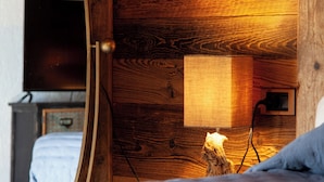 Ein Zimmer mit Holzvertäfelung, einem Bett, einem Spiegel, einer Wandleuchte und einem Fernseher.