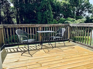 Eine Holzterrasse mit Tisch und zwei Stühlen.
