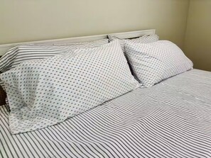 Ein Bett mit gestreifter Bettwäsche und Kissen mit Muster.