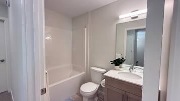 Un baño con ducha, inodoro, lavamanos y mueble.
