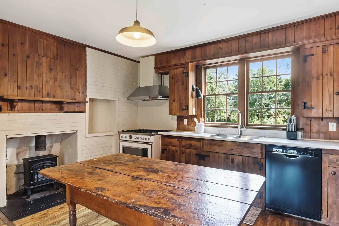 A kitchen with wooden cabinets, a stove, a dishwasher, and a window.