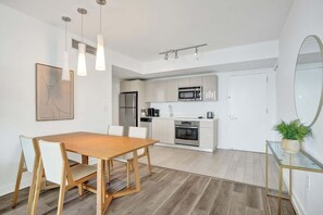 Eine moderne Küche mit weißen Schränken, Edelstahlgeräten und einem Holzespeisetisch mit Stühlen.
