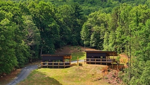 A cabin with a deck and a covered area, surrounded by dense forest and a clear sky. - Cozy 1 bedroom cabin with a hot tub in the mountains of Elizabethton (Elizabethton)