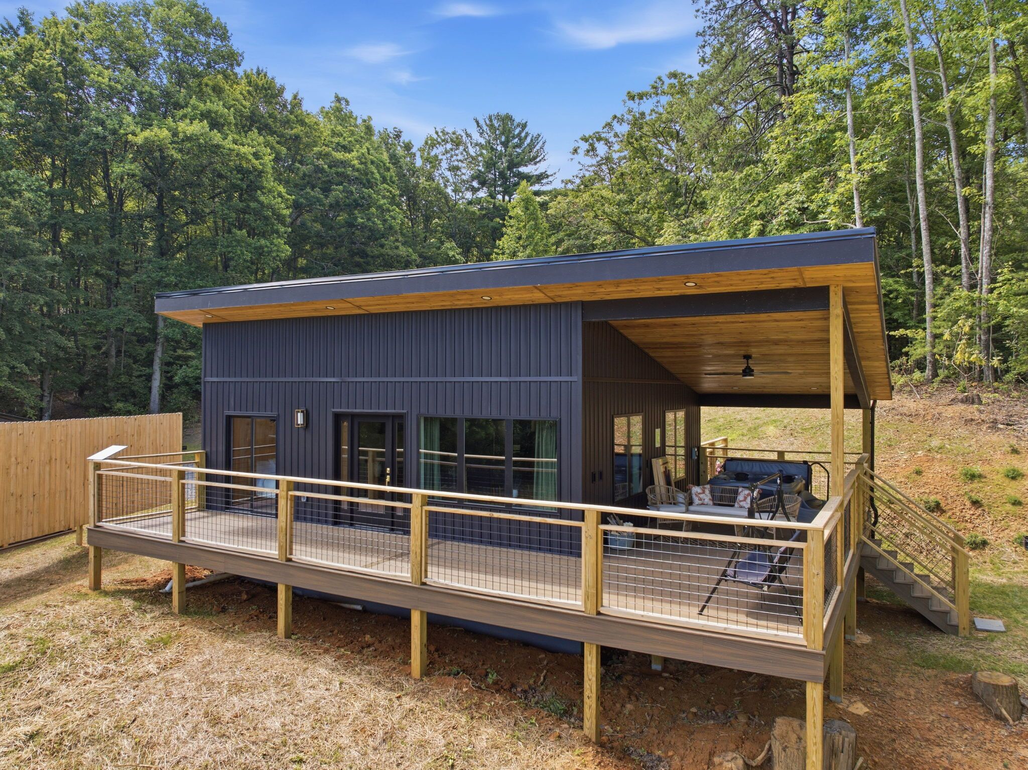 A modern cabin with a deck, large windows, and a covered outdoor area.