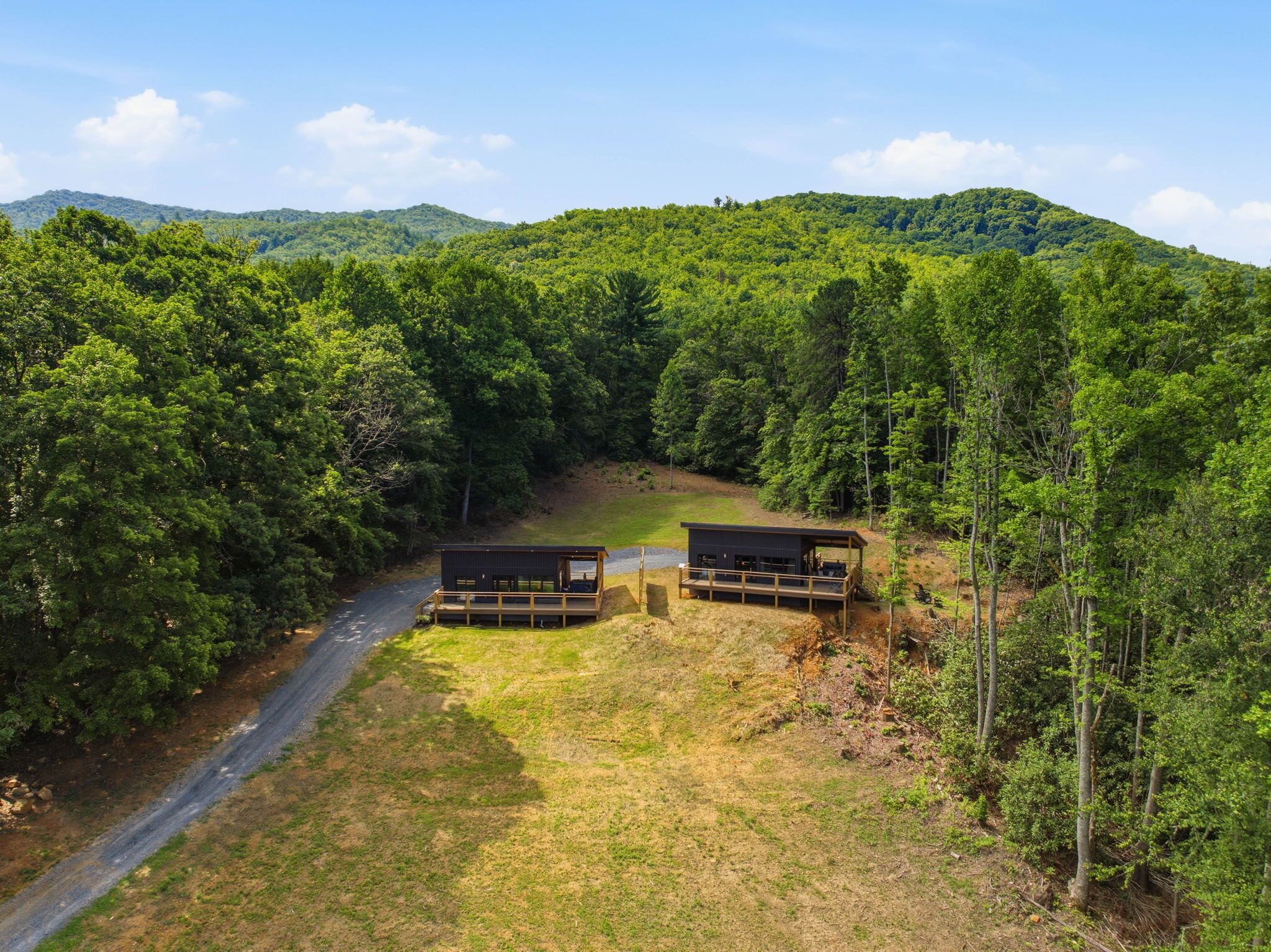 A cabin with a deck, surrounded by dense forest and a clear sky.