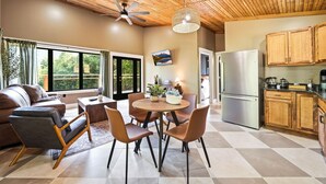 A modern kitchen with wooden cabinets, a stainless steel refrigerator, and a dining area with a round table and chairs. - Cozy 1 bedroom cabin with a hot tub in the mountains of Elizabethton (Elizabethton)