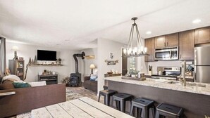 Una cocina moderna con una isla central, taburetes de bar y estufa integrada.