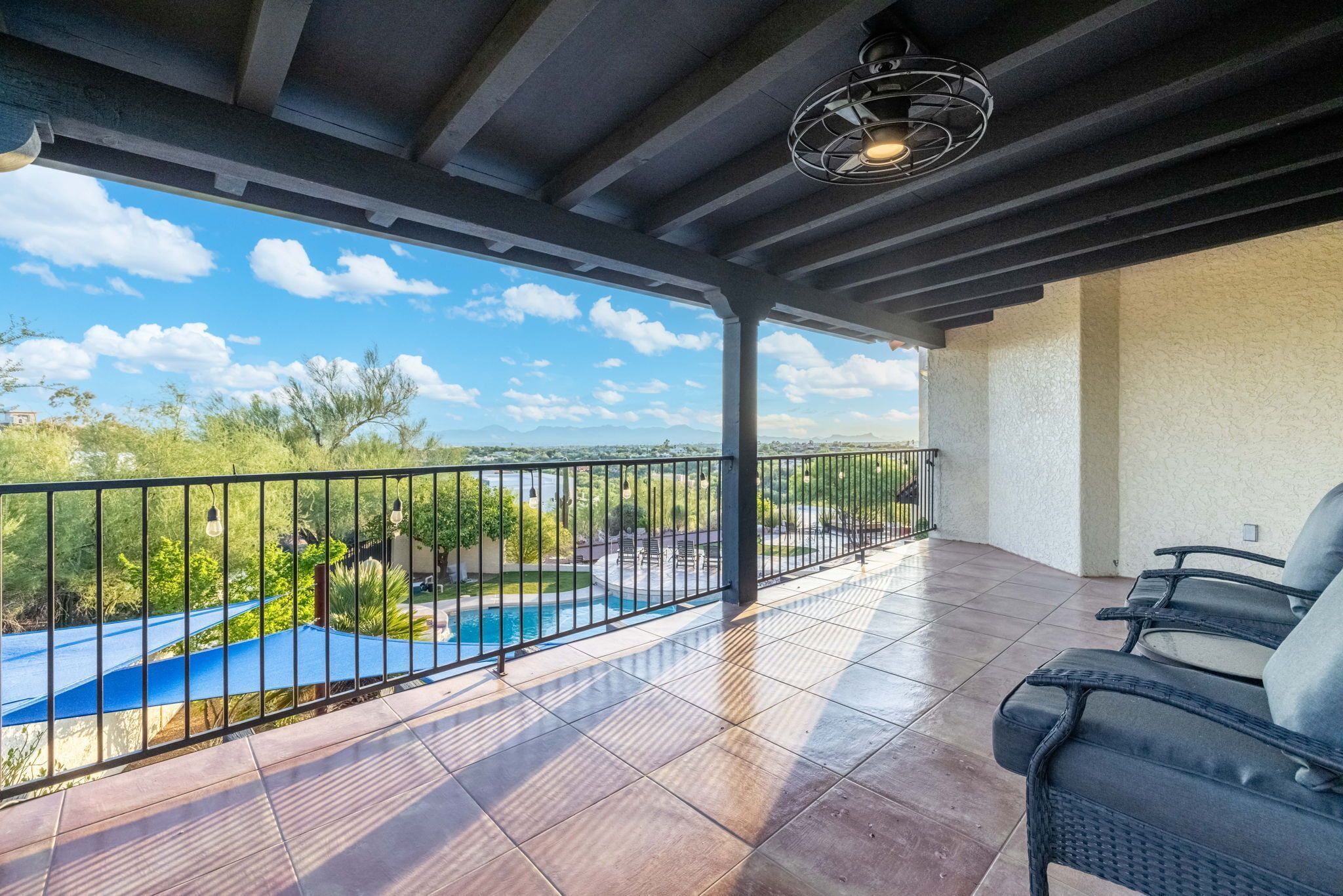 A covered outdoor area with a pool, chairs, and a view of the landscape.