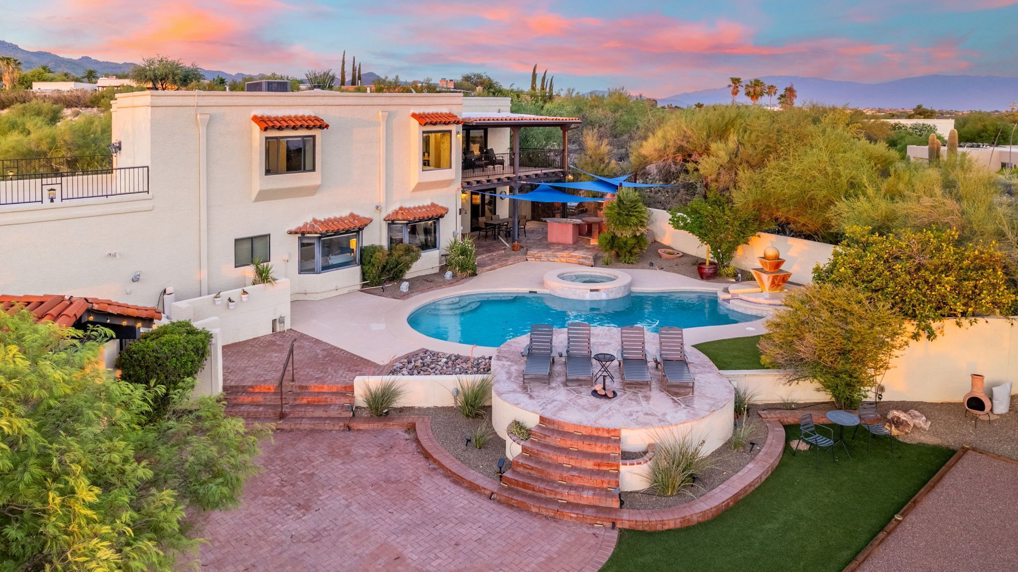 A residential property with a swimming pool, outdoor seating, and a patio area.