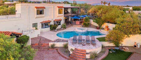 A residential property with a swimming pool, outdoor seating, and a patio area.