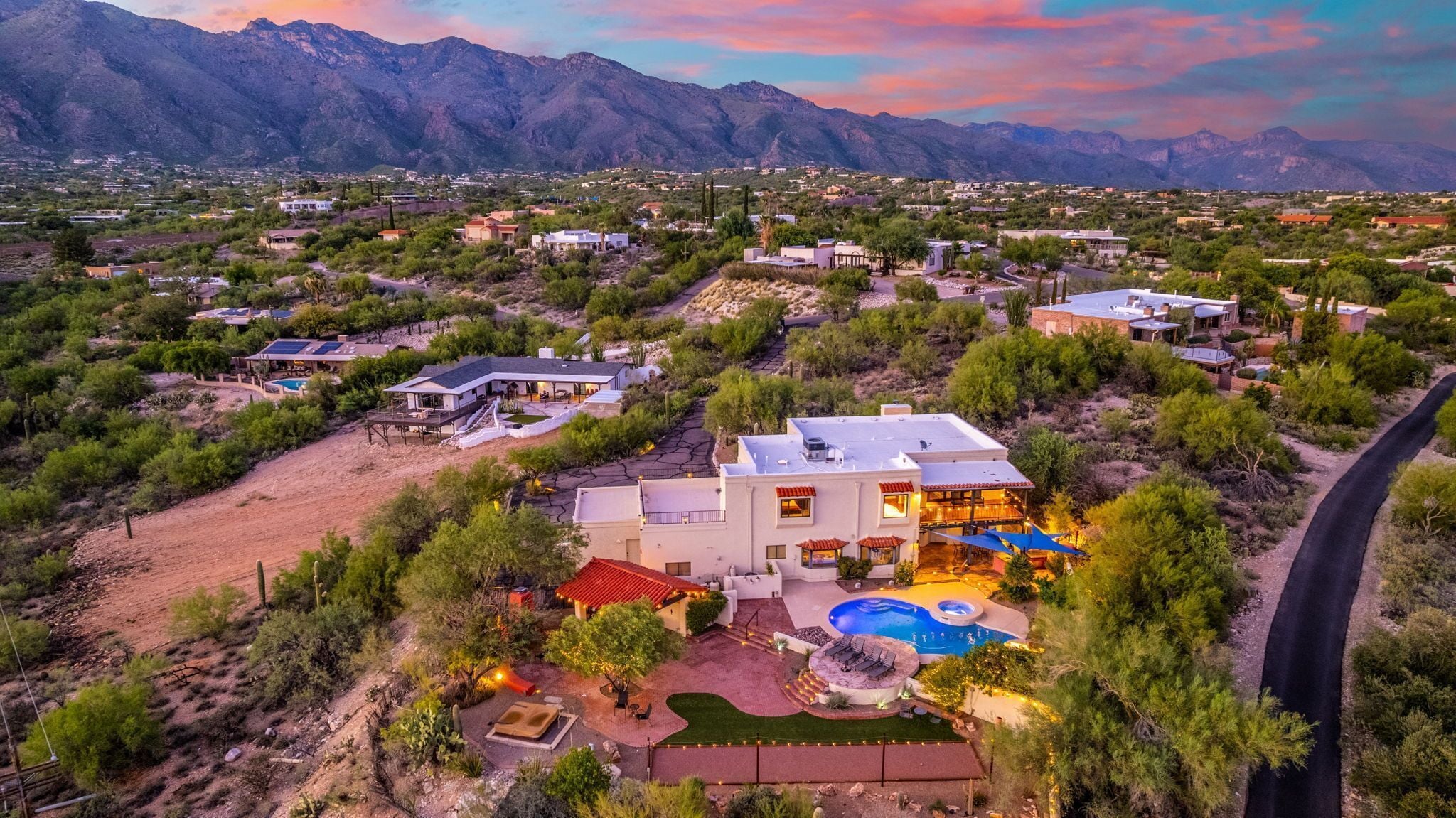 A residential area with houses, a swimming pool, and mountains in the background.