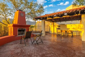 Une terrasse extérieure dotée d’un barbecue, d’un espace salon et d’une structure en forme de pergola.