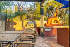 An outdoor patio with a grill, a pizza oven, and a dining table with chairs. - Sundance  Resort Style Home in the Foothills (Tucson)