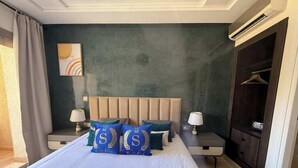 Hotellihuone, jossa on suuri sänky, kaksi yöpöytää valaisimineen, tummanvärinen vaatekaappi ja taulu seinällä.