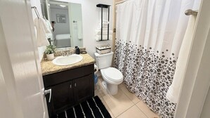 Un baño con lavamanos, inodoro y cortina de ducha.