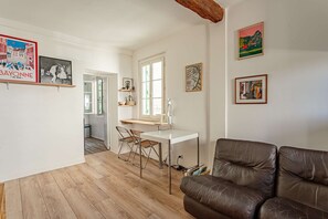 Ein Zimmer mit einem weißen Schreibtisch, einem braunen Ledersofa und einem Essbereich mit Stühlen.