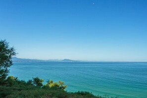 Eine Küstenlandschaft mit freiem Blick auf das Meer und ferne Berge.