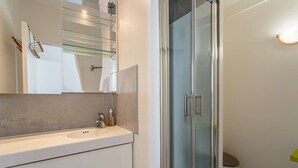A modern bathroom with a glass shower enclosure, a white sink, and a toilet. - Charming studio just a stone's throw from Les Halles and the beaches (BIARRITZ)