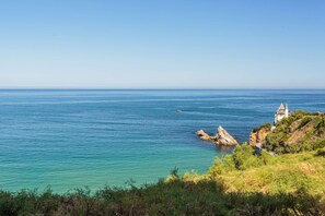 A coastal landscape with clear blue sea, rocky outcrops, and a small building on a cliff. - Charming studio just a stone's throw from Les Halles and the beaches (BIARRITZ)