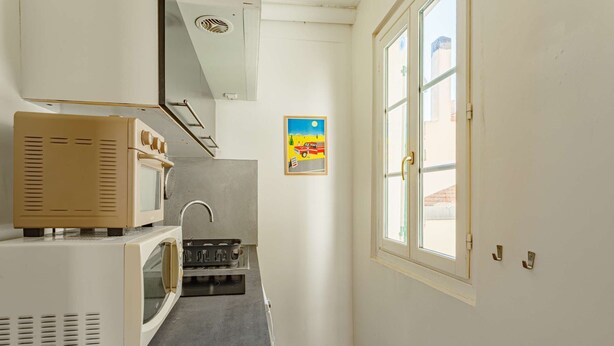 A compact kitchen with a microwave, stove, and sink. - Charming studio just a stone's throw from Les Halles and the beaches (BIARRITZ)