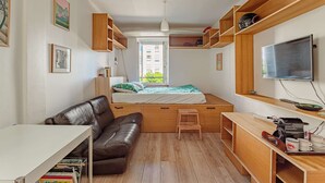 A compact room with a bed, a sofa, a desk, and a TV. - Charming studio just a stone's throw from Les Halles and the beaches (BIARRITZ)