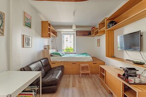 A compact room with a bed, a sofa, a desk, and a TV. - Charming studio just a stone's throw from Les Halles and the beaches (BIARRITZ)