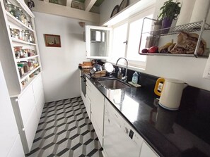 A compact kitchen with white cabinets, a black countertop, a sink, and a window. - SAINT-JEAN DE LUZ, CENTRE HISTORIQUE, QUAI DE L'INFANTE (ST JEAN DE LUZ)