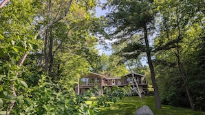 A two-story wooden cabin surrounded by dense forest.