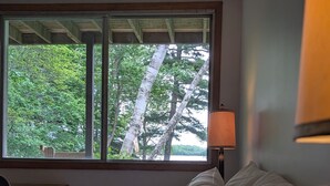 A bedroom with a large window, a desk, and a lamp.