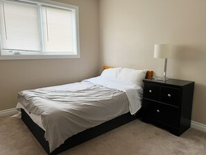 A bedroom with a single bed, a nightstand, a lamp, and a window with blinds. - Luxury 3beds 3bath condo(over 30D 10% discount) (Saskatoon)