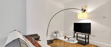 A modern living room with a sofa, a coffee table, a TV on a stand, and a floor lamp.