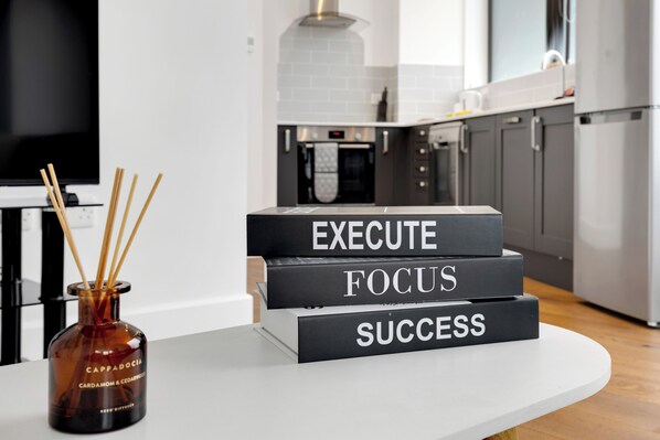 A kitchen with a white countertop, a diffuser with reed sticks, and three black boxes stacked with motivational words. - Spacious Flat (ground floor) in Lambeth with gated parking (London)