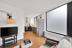 A modern living room with a flat-screen TV, a coffee table with books, and a sofa. - Spacious Flat (ground floor) in Lambeth with gated parking (London)