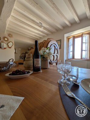 A dining table with a bottle of wine, a bowl of cherries, and a vase of flowers. - Alice's House - TERNAND (TERNAND)