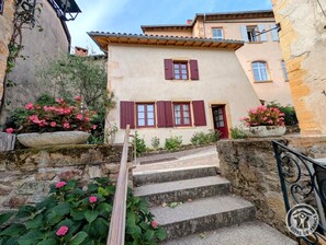 A stone staircase leading to a building with red shutters and a door, surrounded by greenery and flowers. - Alice's House - TERNAND (TERNAND)