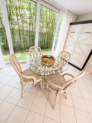 A glass-top dining table with wicker chairs, a woven basket, and a view of bamboo outside. - Coastal Retreat located on Manasota Key, Heated Pool, Beach & Bay Access (Englewood)