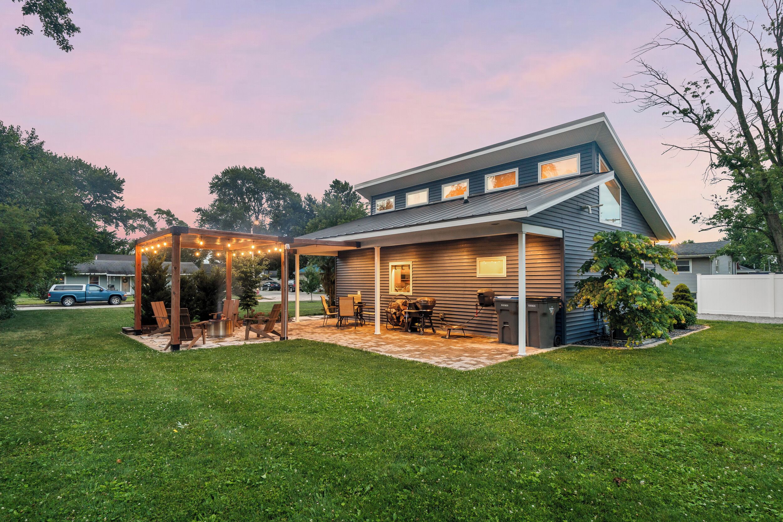 Een modern huis met een overdekt terras, een barbecueplaats en een verzorgd gazon.