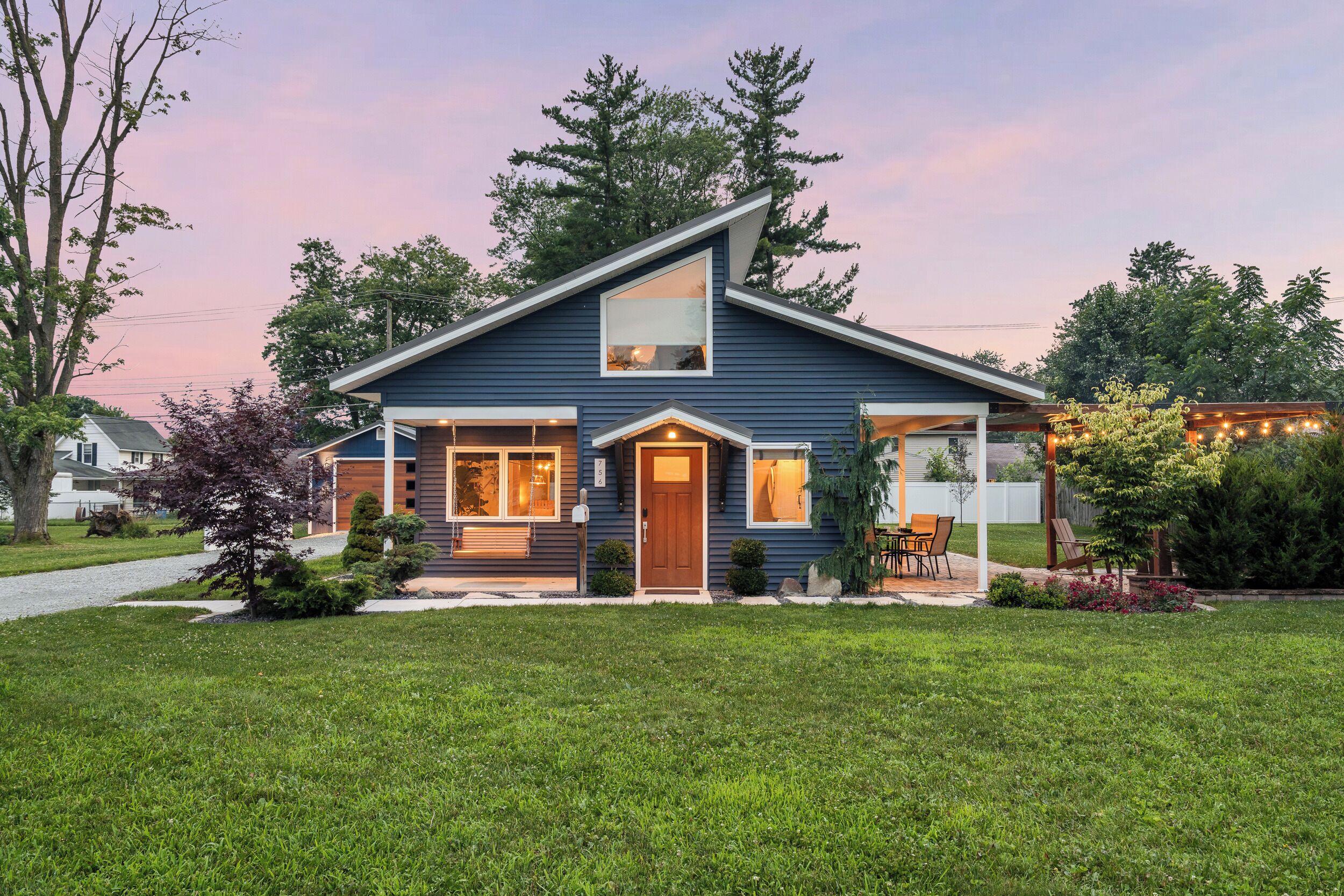 A modern two-story house with a sloped roof, a front porch, and a well-maintained lawn.