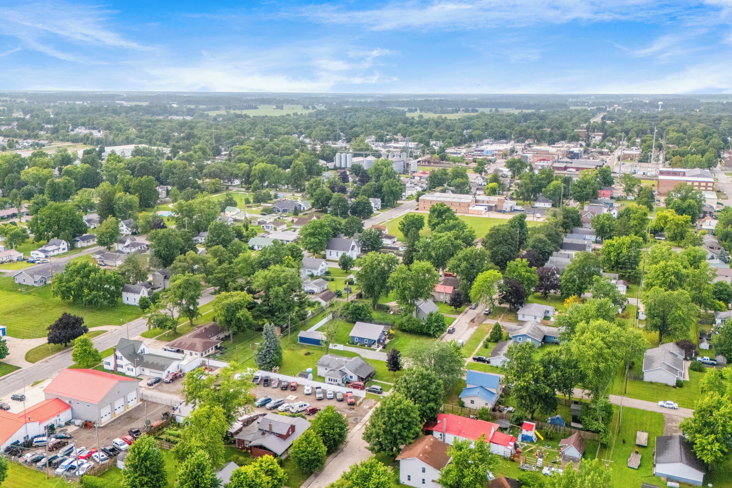 An aerial view of a residential area with houses, a parking lot, and a large building with a red roof.