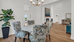 A dining area with a chandelier, floral chairs, a large potted plant, and a view to the dining room. - Remodeled 4BDR Home with Valley Views & Hot Tub (Draper)