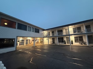 Ein mehrstöckiges Motel mit Parkplatz, Außenbereich und überdachtem Bereich.