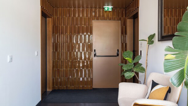 A hotel lobby with a wooden partition, a reception desk, a chair with a cushion, and a large plant. - Cosy Studio | Custom Tiles & Balcony · Leiria (Leiria)