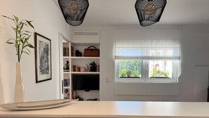 A modern kitchen with a white countertop, a large window with a view of greenery, and a bamboo plant. - Cosy Studio | Custom Tiles & Balcony · Leiria (Leiria)