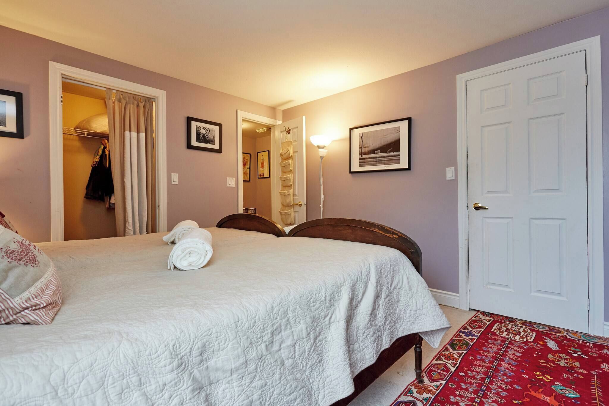 A bedroom with a bed, a wardrobe, a door, and a hallway.