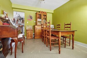 A dining area with a wooden table and chairs, a cabinet with glass doors, and a piano. - Room-french Nest, Private Bathroom! Chec (Burlington)