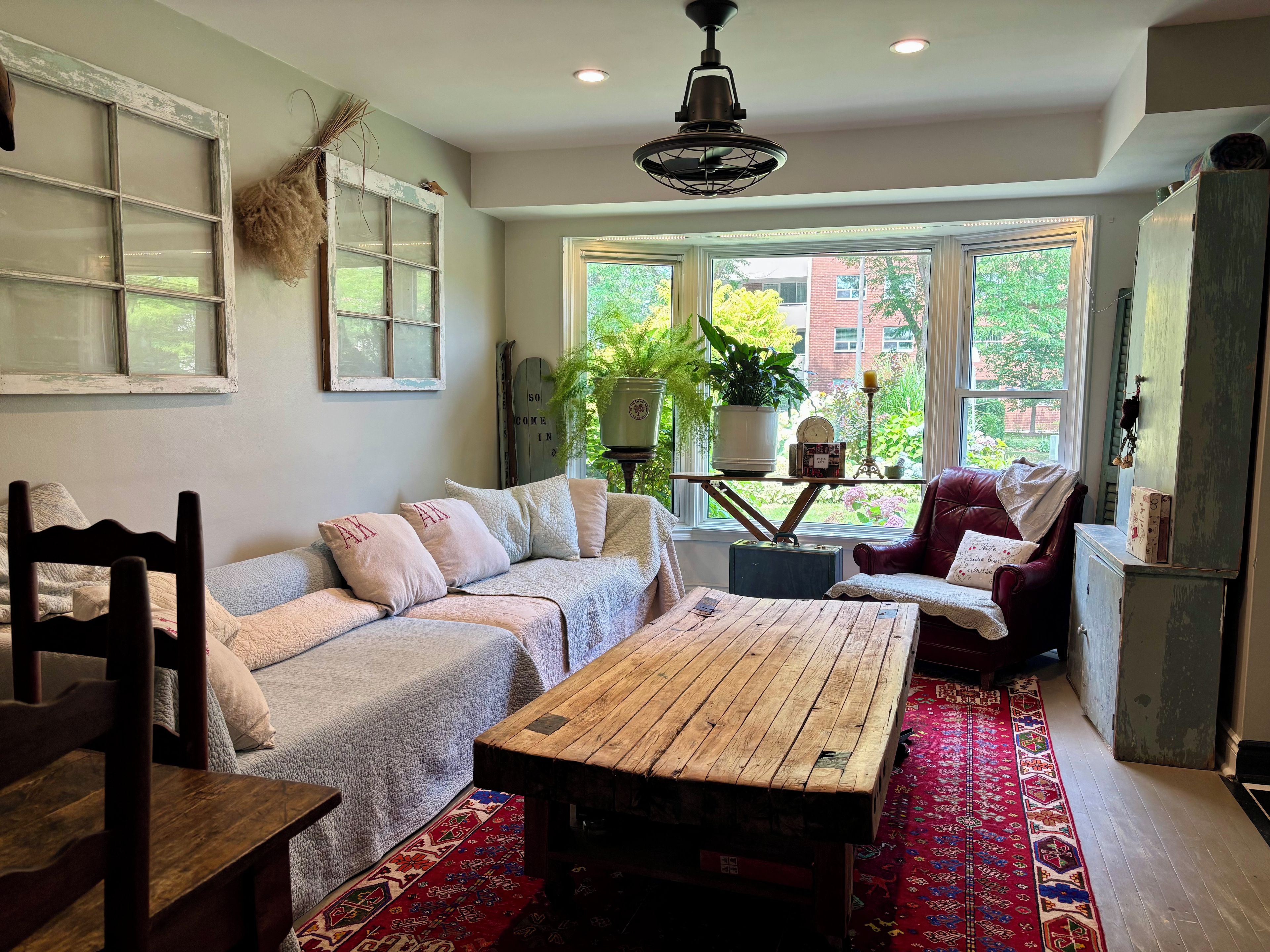 A cozy living room with a sofa, a wooden coffee table, and a red patterned rug.