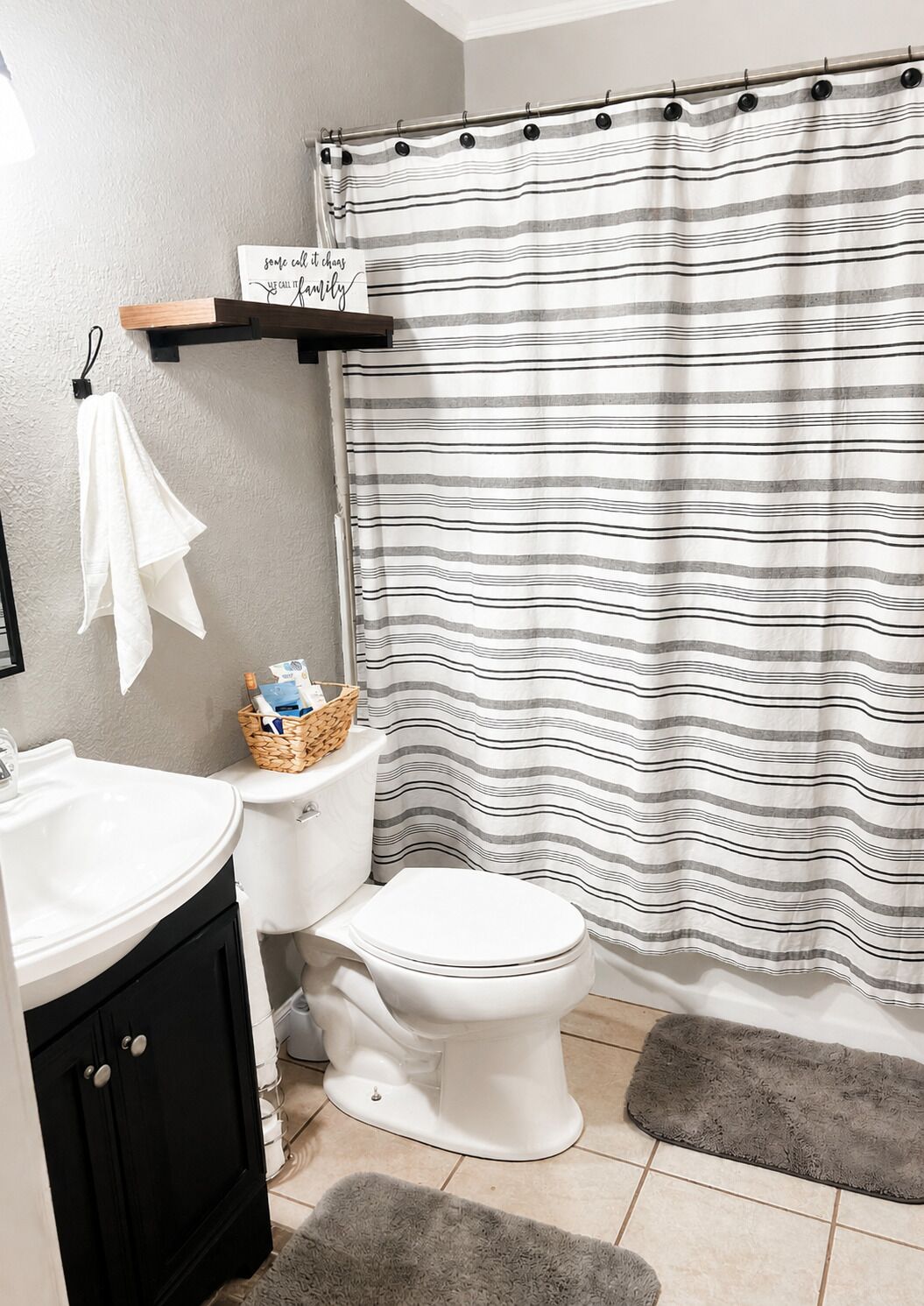A bathroom with a striped shower curtain, a white toilet, a sink, and a towel rack.